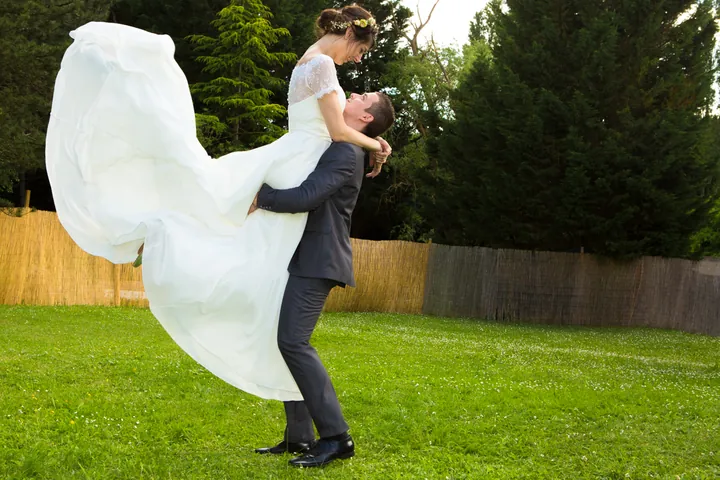 Le marié soulève sa mariée dans un jardin