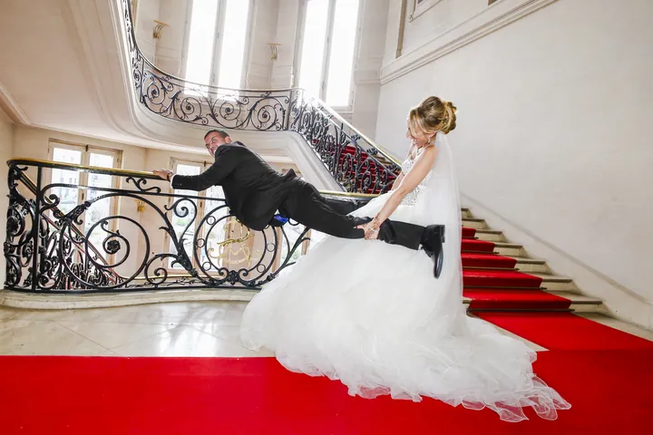 Mariés dans l'escalier d'honneur d'un château, sur le tapis rouge
